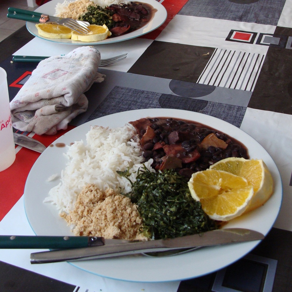 Before: the feijoada plate on a cluttered table with cutlery and a napkin