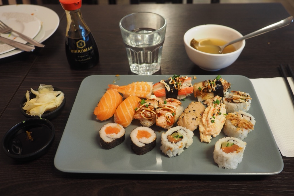 Before: the sushi plate on a dark restaurant table with glasses and bowls around it